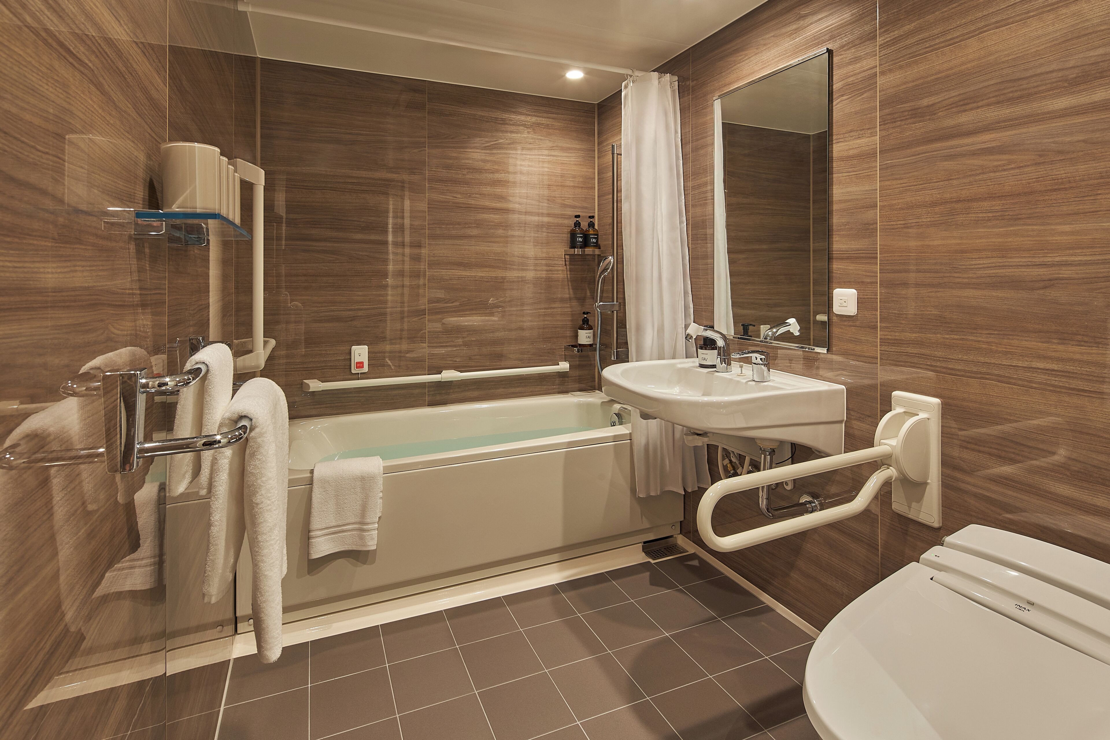 A modern bathroom with a bathtub, shower, and toilet.