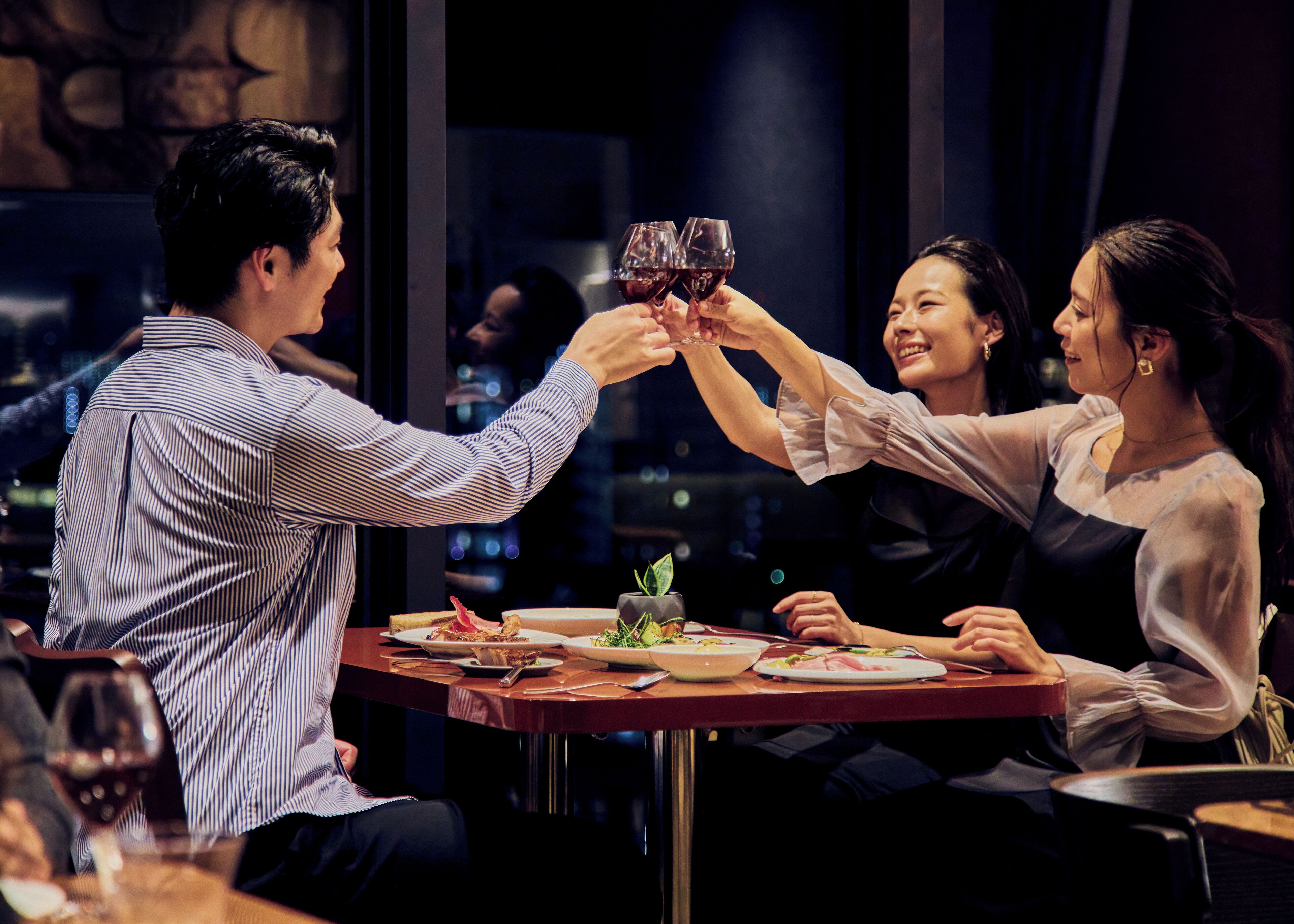 A group of people toasting with wine glasses at a dinner table in a restaurant.