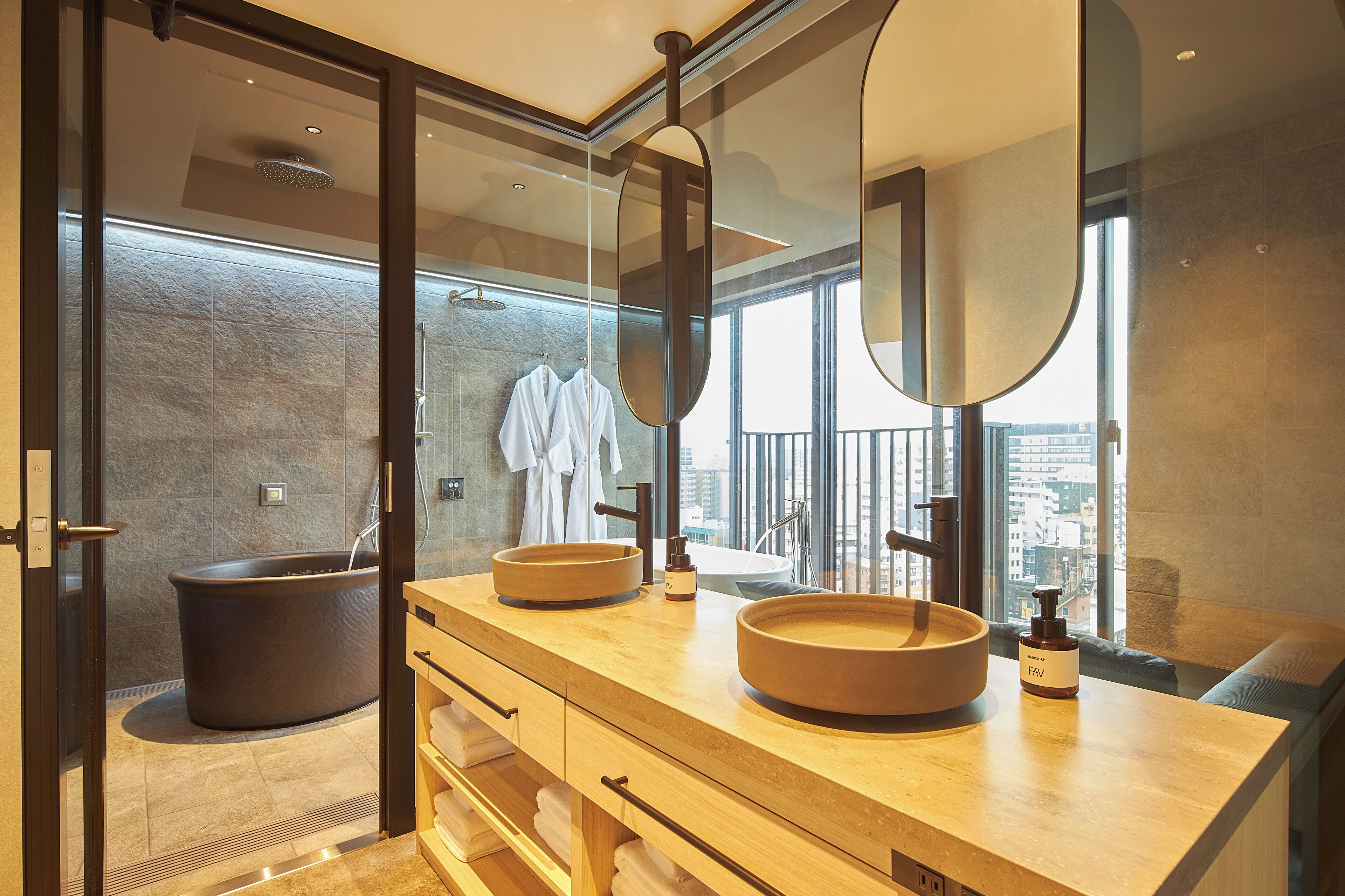 A modern bathroom with a large mirror, two sinks, and a bathtub.
