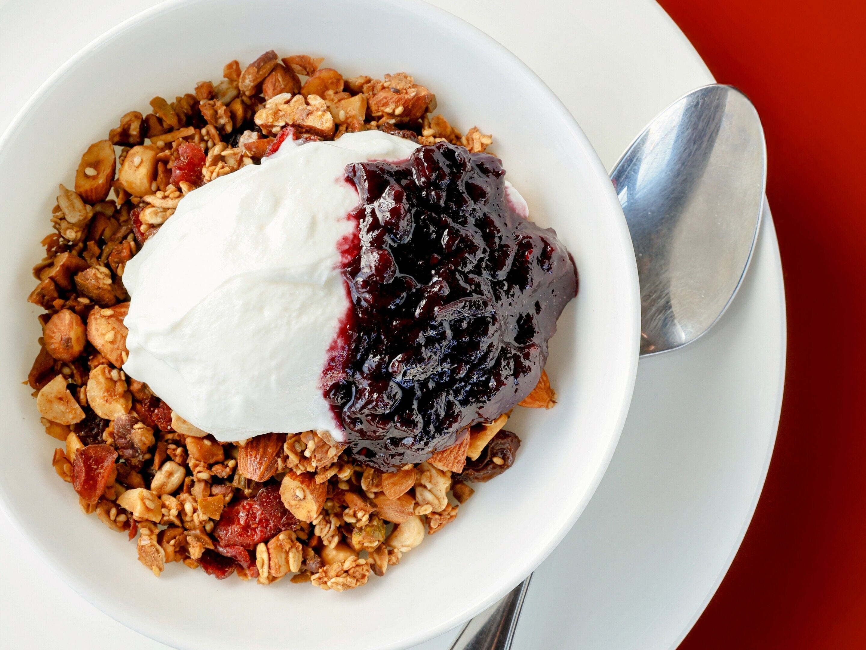 A bowl of granola with yogurt and a berry compote.