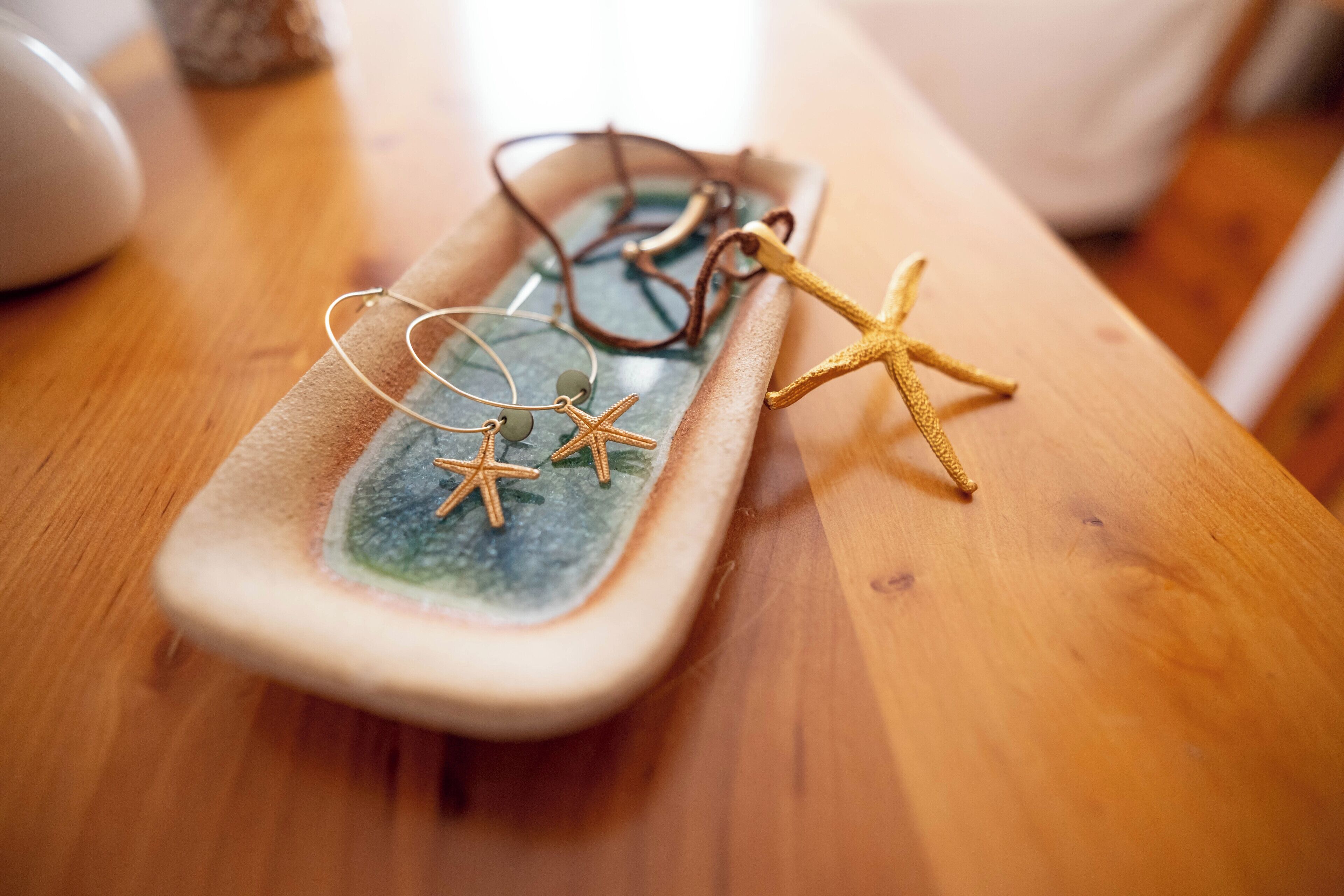 Una bandeja rectangular con superficie de vidrio, que contiene un par de gafas y dos estrellas de mar.