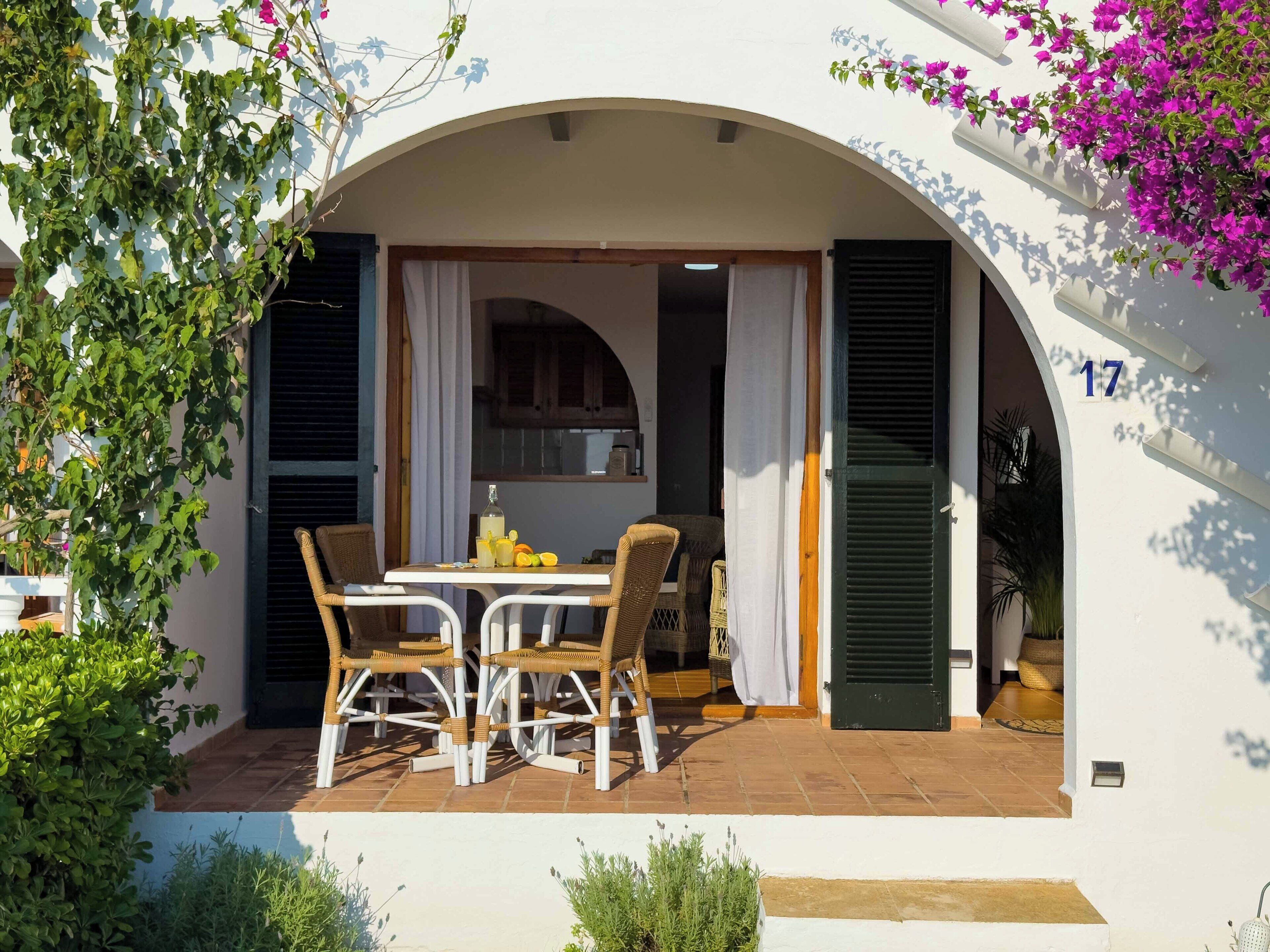 A covered patio with a table and chairs, a view into the house, and a number '17' on the wall.