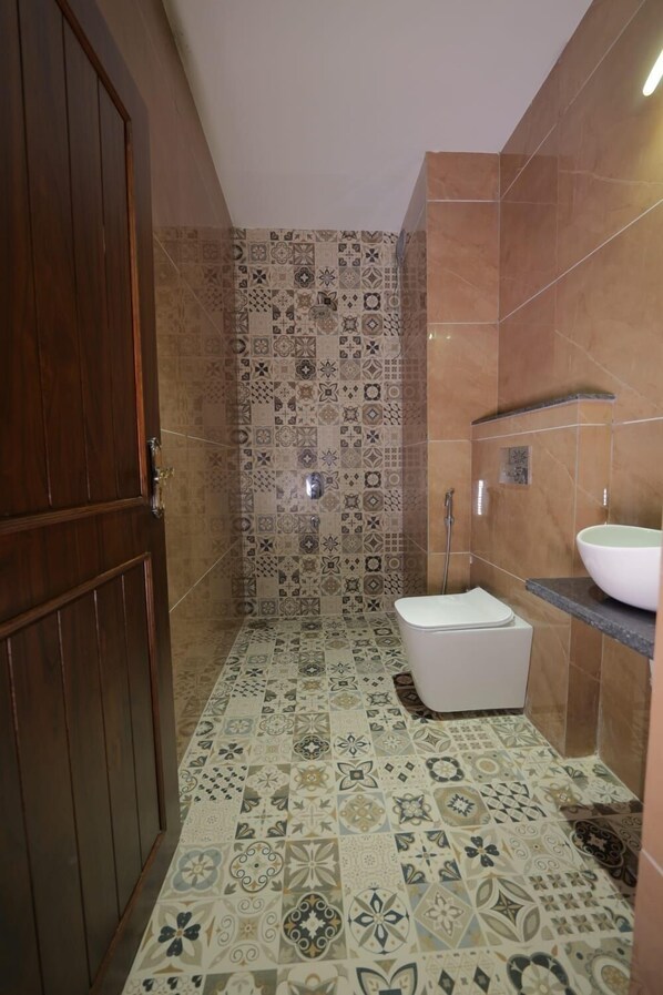 A bathroom with patterned tiles, a toilet, a sink, and a shower. - Shree Raja Ram Hotel & Resort (Ujjain)