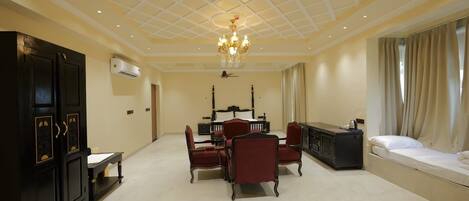 A spacious room with a large bed, a desk, and a dining area.