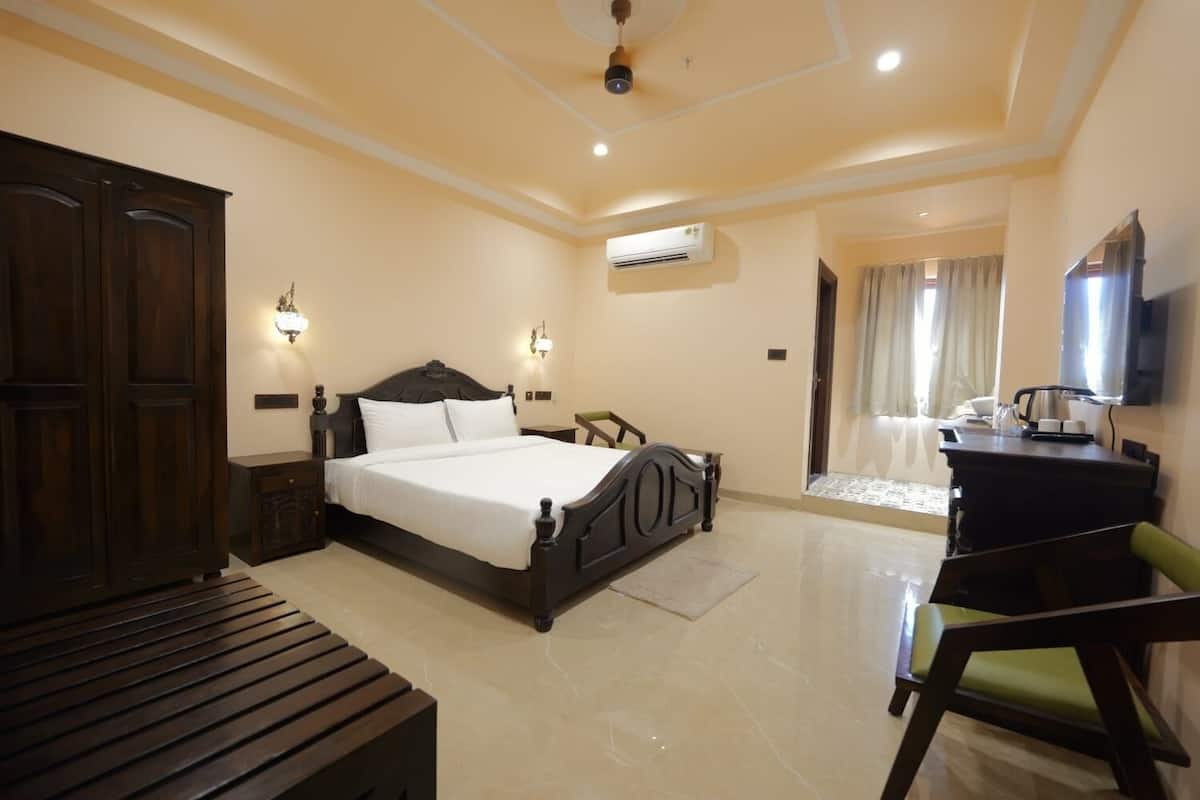 Una habitación de hotel con una cama grande, un escritorio, una silla, un armario y un televisor.
