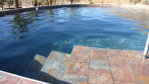 Ein klarer Pool mit Steinplatten am Rand.