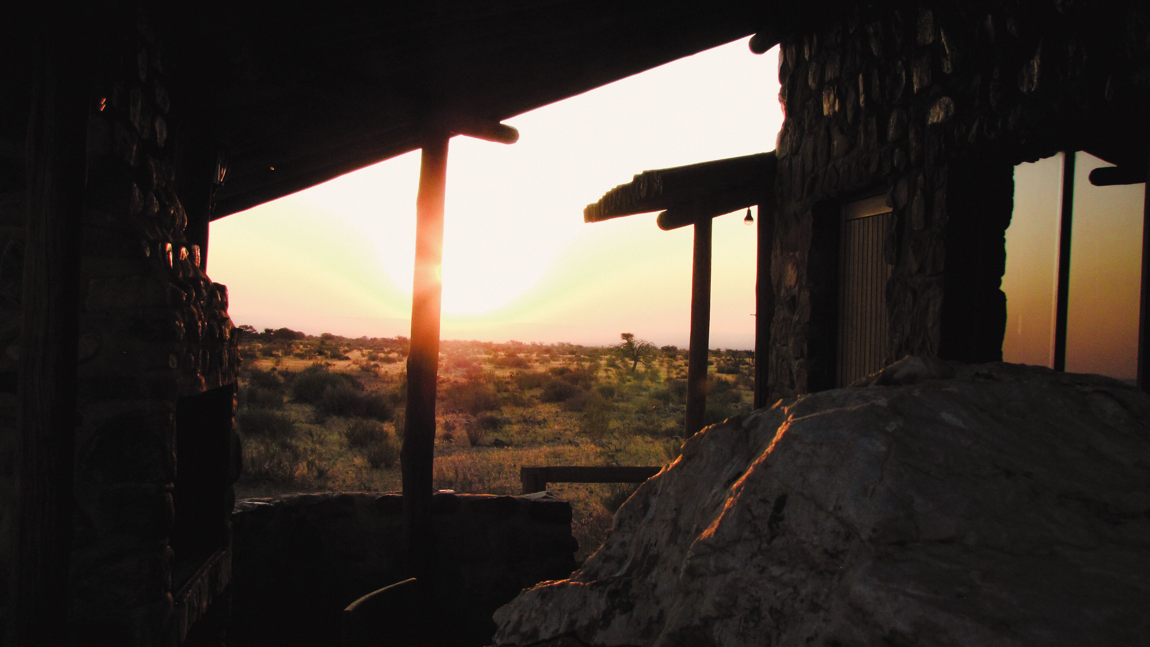A rustic building with a stone exterior and a wooden structure in the foreground.