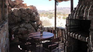 Eine Terrasse im Freien mit Steinmauern, einem runden Tisch und Stühlen.