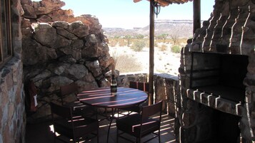 Un patio al aire libre con paredes de piedra, una mesa redonda y sillas.