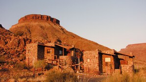 Ein rustikales Steinhaus mit mehreren Zimmern in einer trockenen, hügeligen Landschaft.