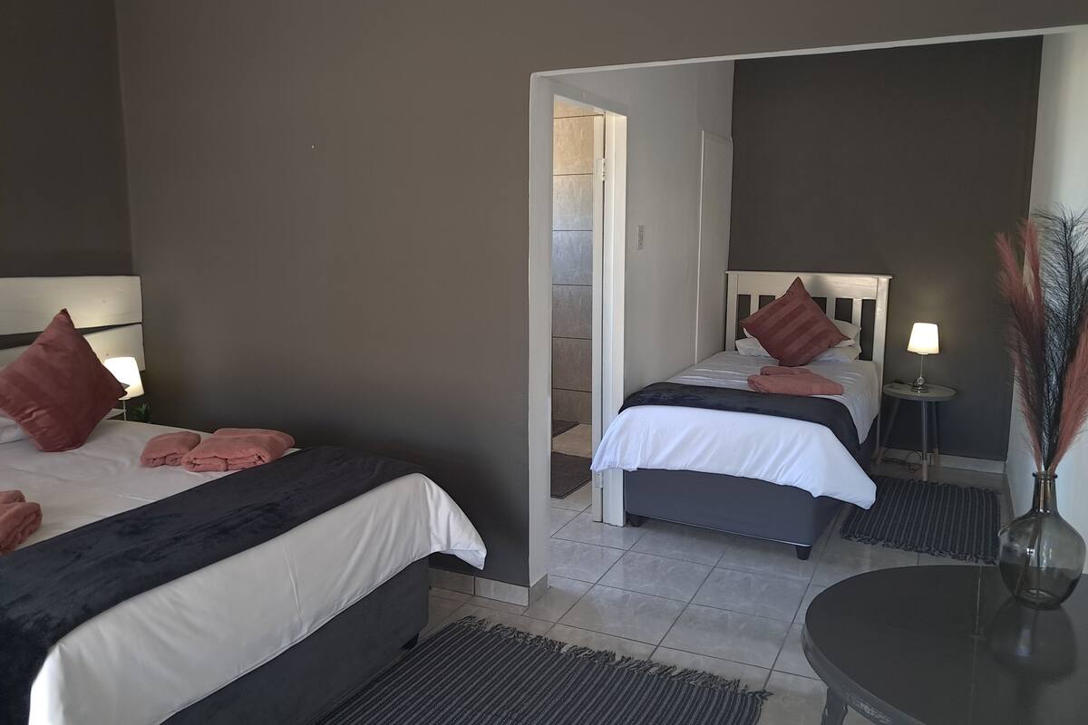 Une chambre d’hôtel avec deux lits, une petite table, une lampe et un vase.