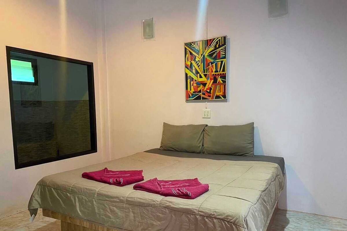 Une chambre à coucher avec un lit, des oreillers, une fenêtre et un tableau au mur.