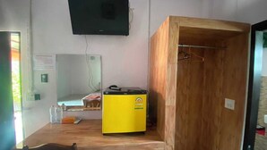 A room with a wooden table, a yellow refrigerator, a television mounted on the wall, and a wooden door. - OYO 75524 SK Resort (Nuea Khlong)