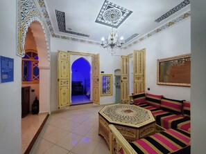 A room with a traditional design, featuring a patterned sofa, a decorative ceiling, and a chandelier. - Hotel Blue City (Chefchaouen)