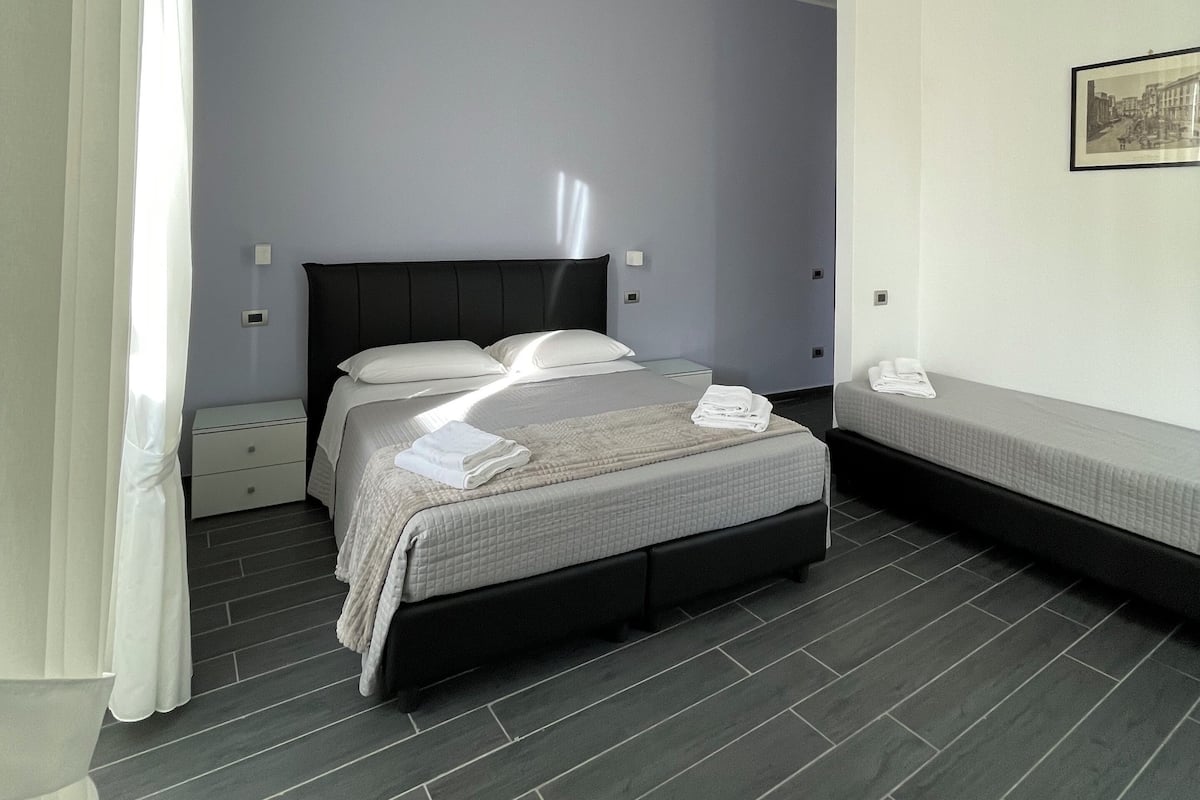 A modern bedroom with a bed, bedside tables, and a wall-mounted picture.
