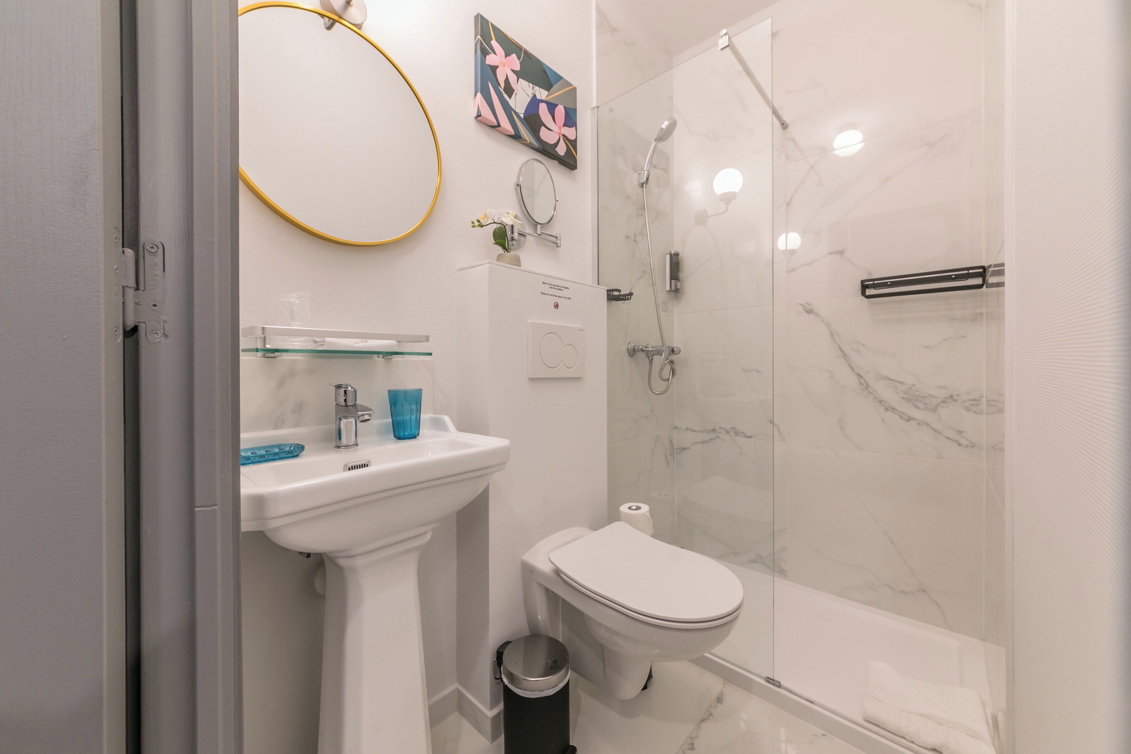 Une salle de bain moderne avec un lavabo, des toilettes et une douche, le tout de couleur blanche.