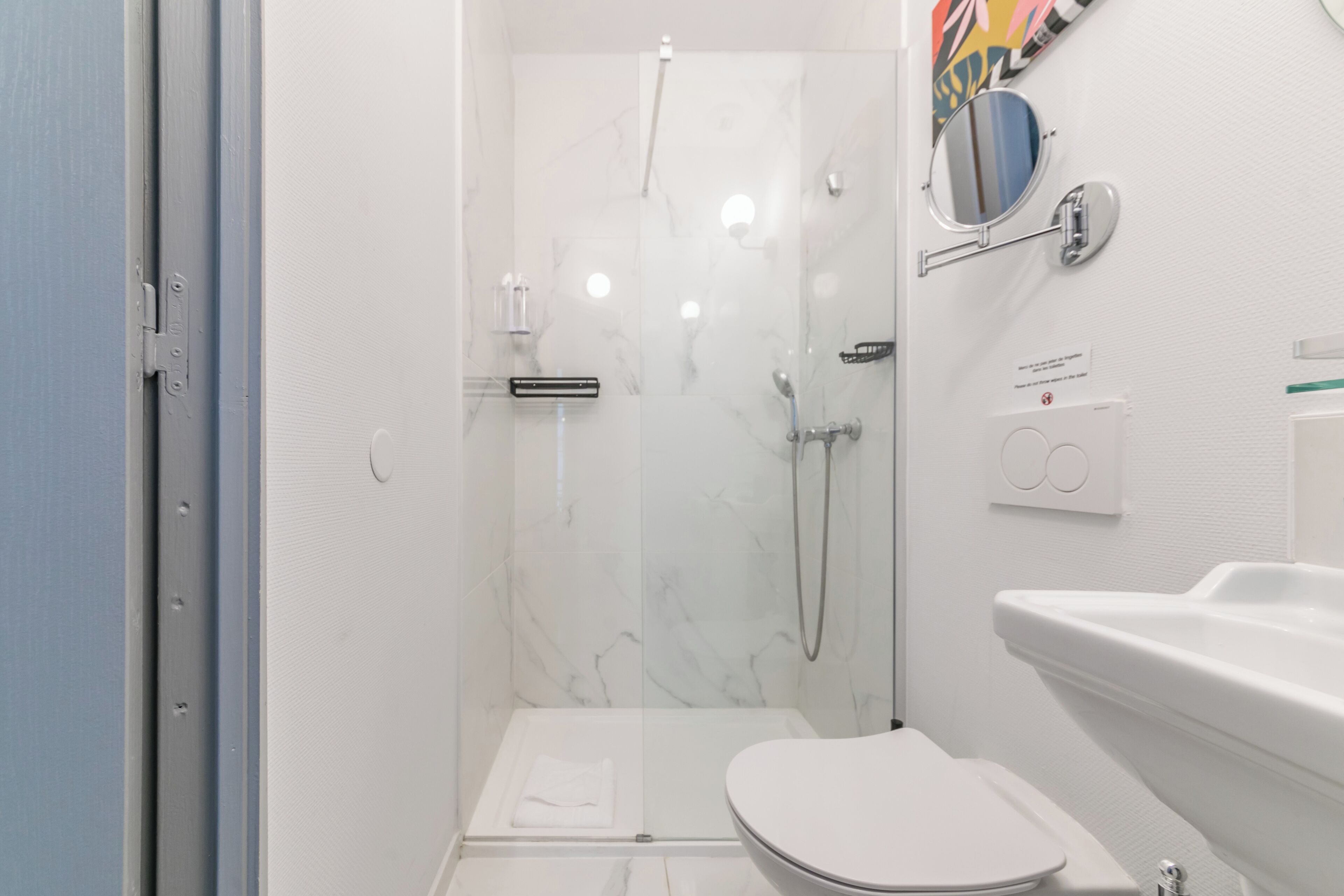 Ein modernes Badezimmer mit einer Duschkabine aus Glas, einer weißen Toilette und einem Waschbecken mit Spiegel.