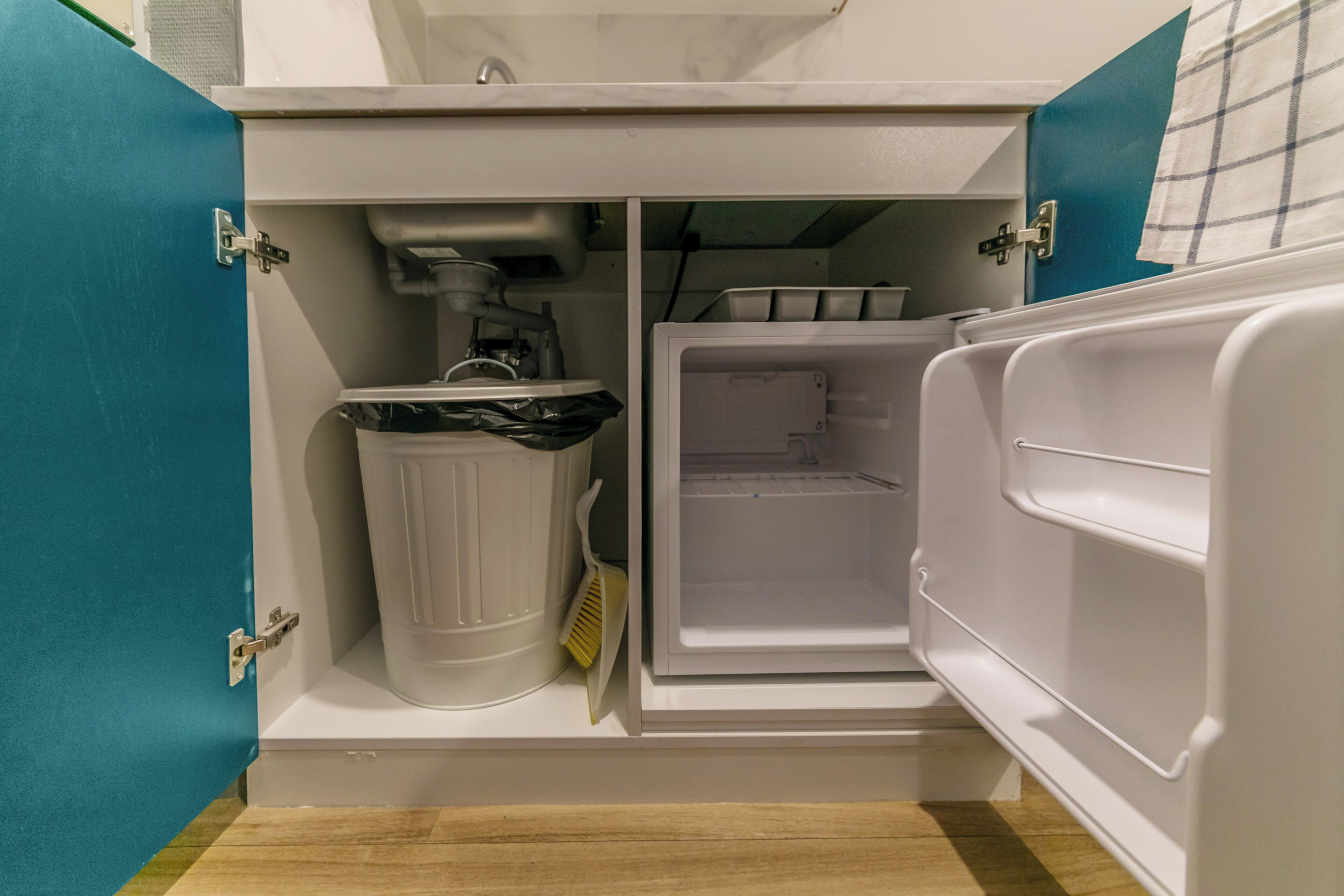 Une cuisine compacte dotée d’un réfrigérateur intégré et d’une poubelle.