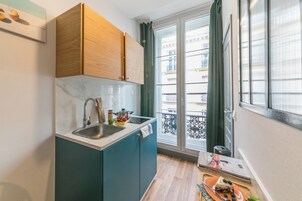 A compact kitchen with a sink, wooden cabinets, and a window with a view of buildings.
