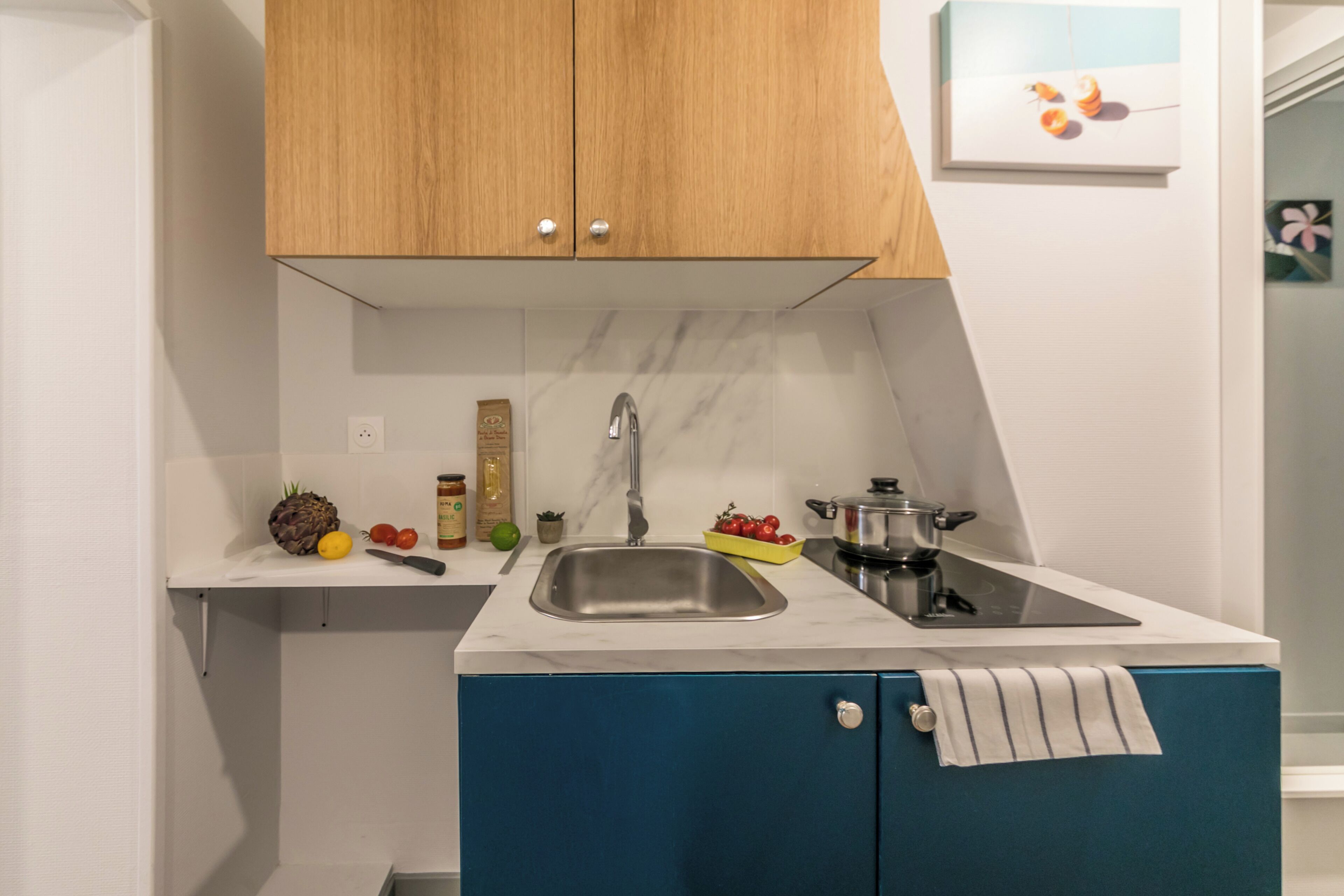 A kitchen with a sink, wooden cabinets, a marble countertop, and various kitchen items.
