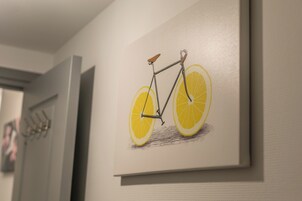 Una obra de arte enmarcada de una bicicleta con rebanadas de limón en lugar de ruedas, colgada en una pared.
