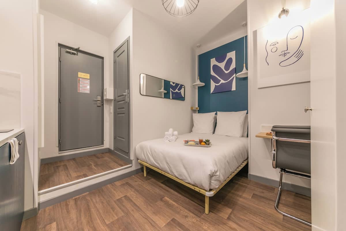 Une chambre d’hôtel moderne comprenant un lit, un espace douche et un petit coin salon.