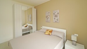 Une chambre à coucher comprenant un lit, une table de chevet, un miroir et deux œuvres d’art murales.