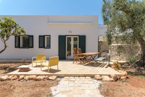 A modern building with a patio area featuring outdoor furniture and a stone pathway. - Ecofriendly Villa Oliva Blu by Wonderful Italy (Ostuni)