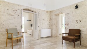 Ein Zimmer mit Steinwänden, einem weißen Heizkörper und zwei Holzsesseln.