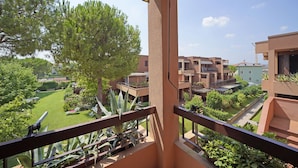 A balcony with a view of a courtyard, including a tree and a building with multiple balconies. - Residence Riviera 43 by Wonderful Italy (Desenzano del Garda)