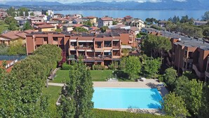Un hotel con piscina rodeado de vegetación, vista a un lago y montañas al fondo.