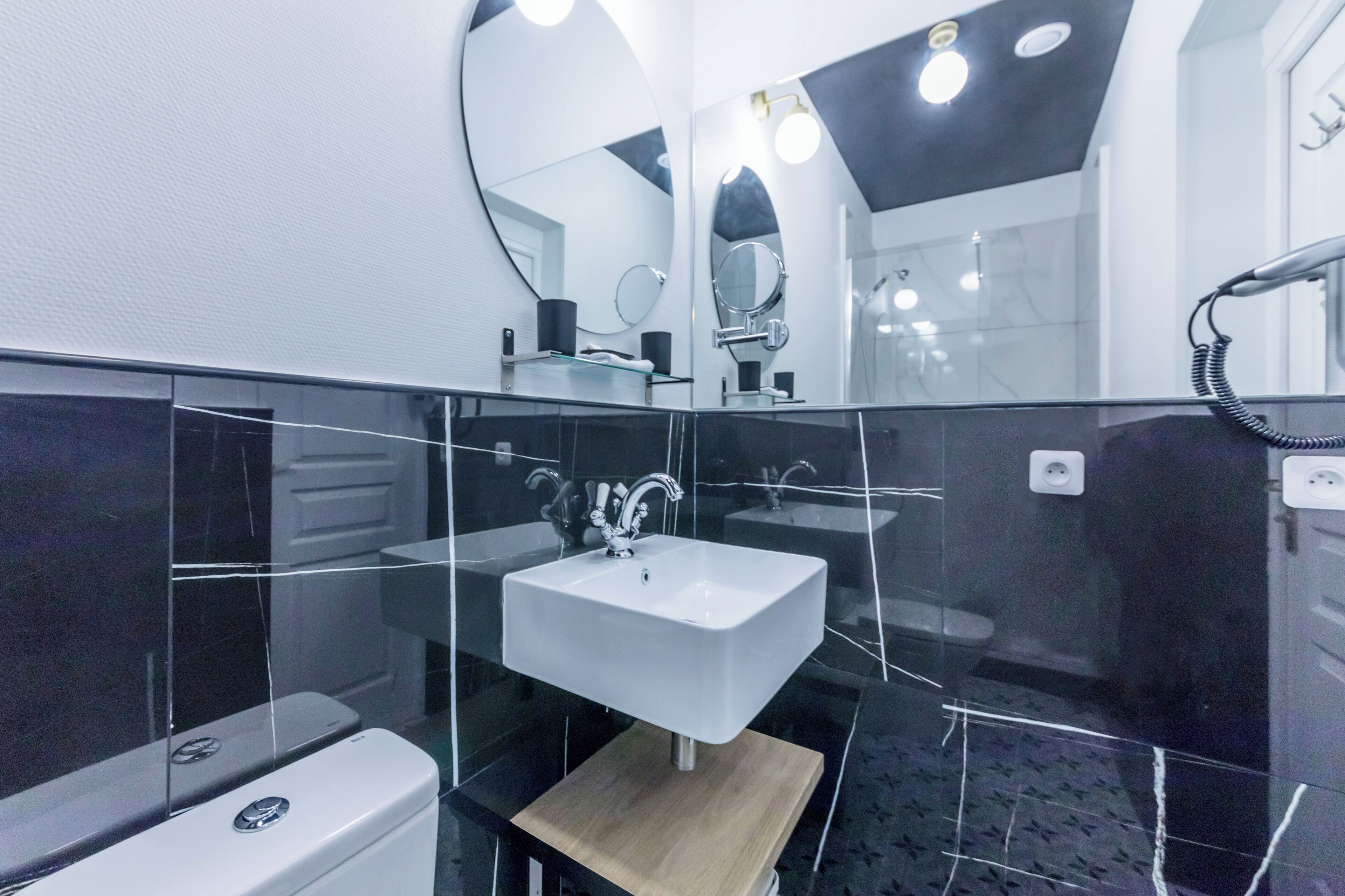 A modern bathroom with a white sink, a mirror, and a handheld showerhead.