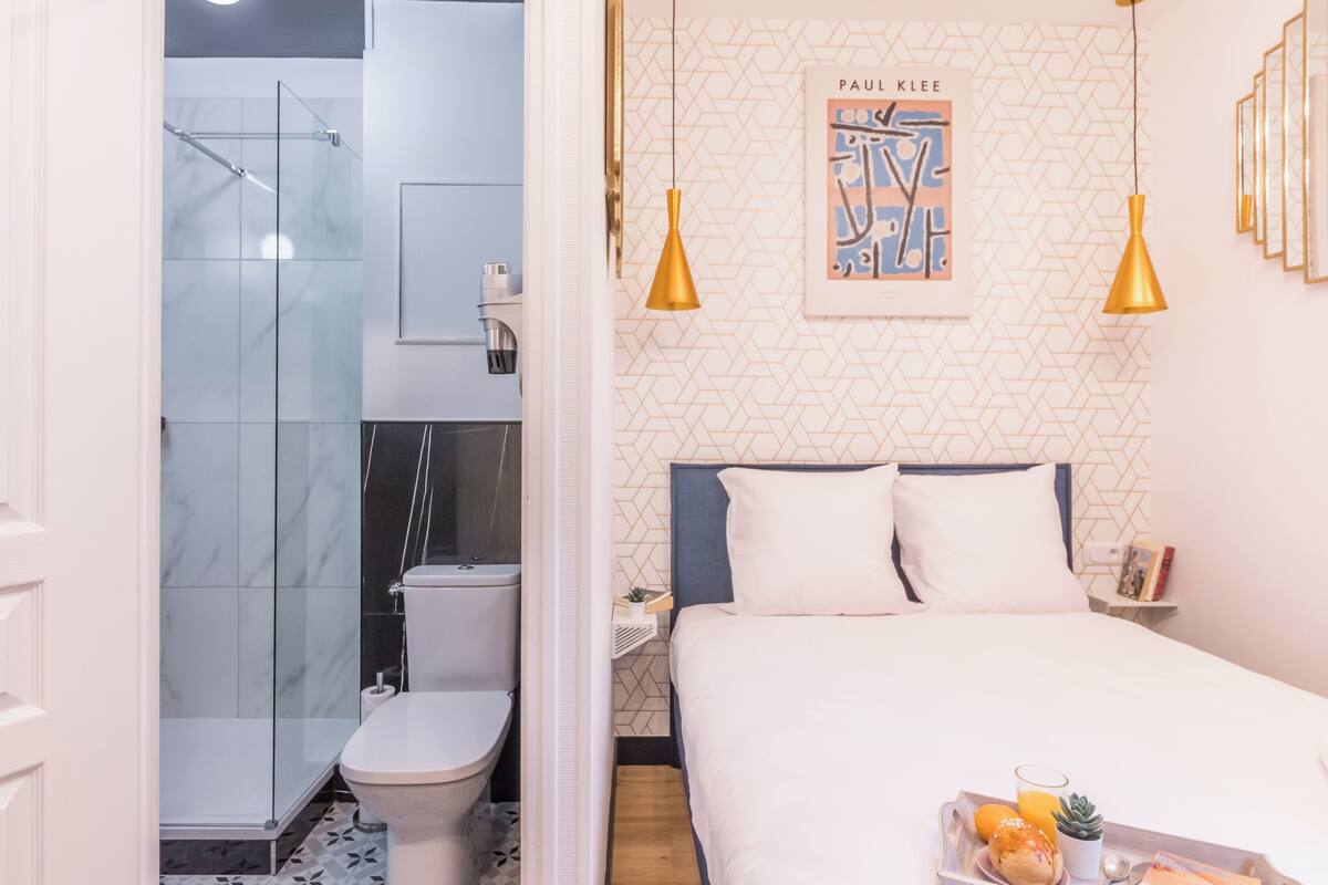 A modern hotel room with a shower, toilet, bed, and breakfast tray.