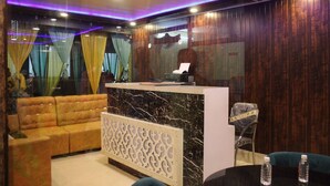 A reception area with a marble counter, a sofa, and a decorative partition. - Hotel Vibrant Lawn And Banquet (Danapur)