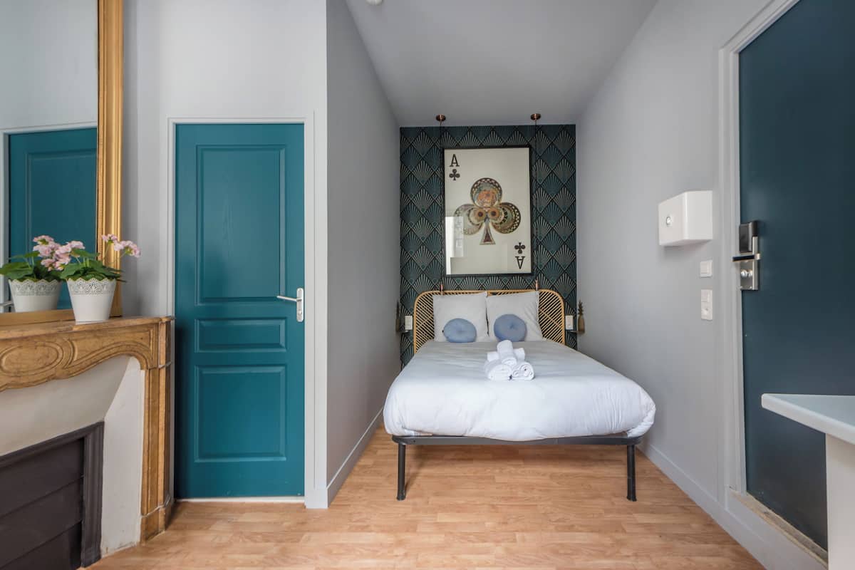 Une chambre à coucher avec un lit, une porte, un miroir et un tableau accroché au mur.