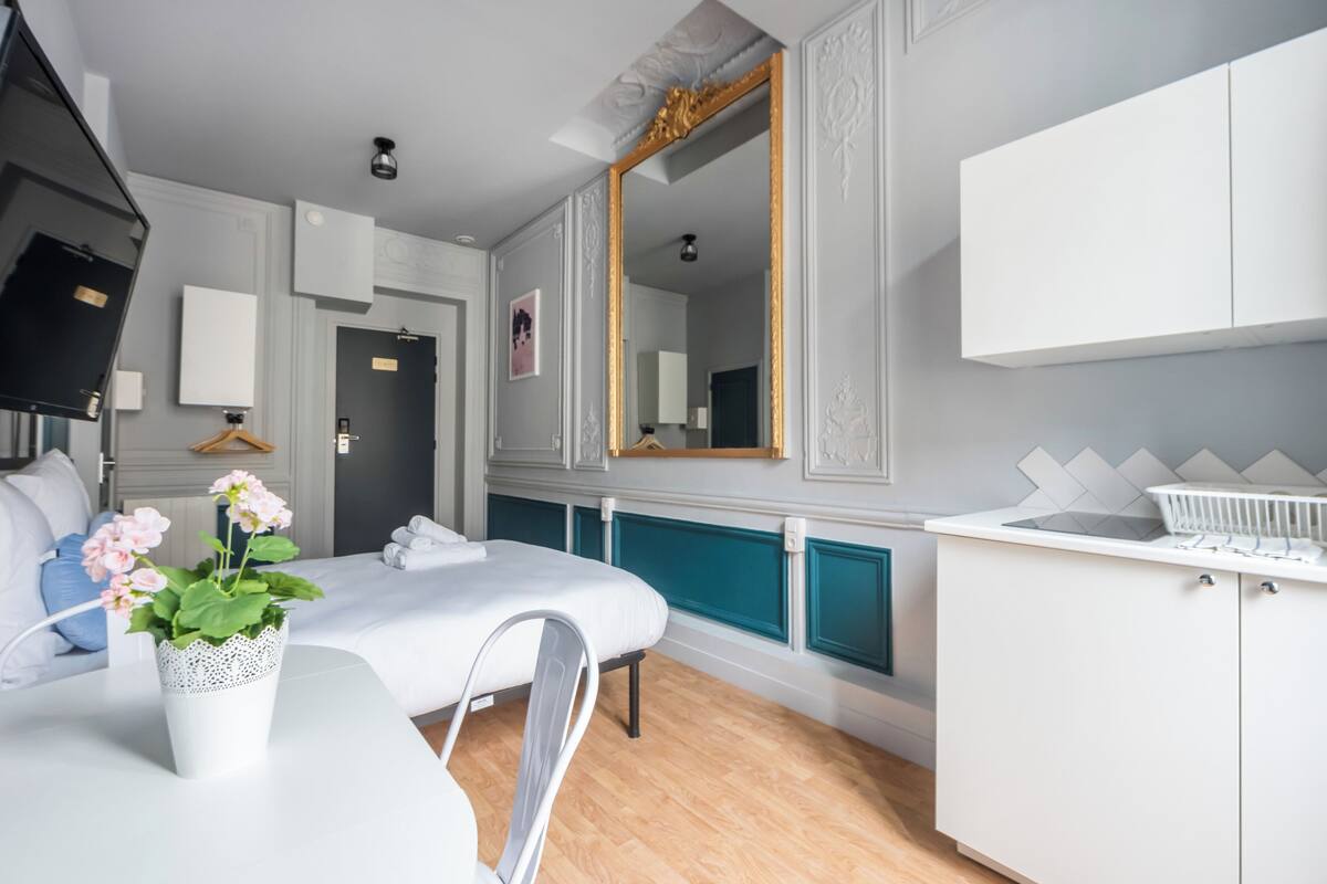 Une chambre d’hôtel moderne avec un lit, un bureau blanc, un miroir et une armoire.