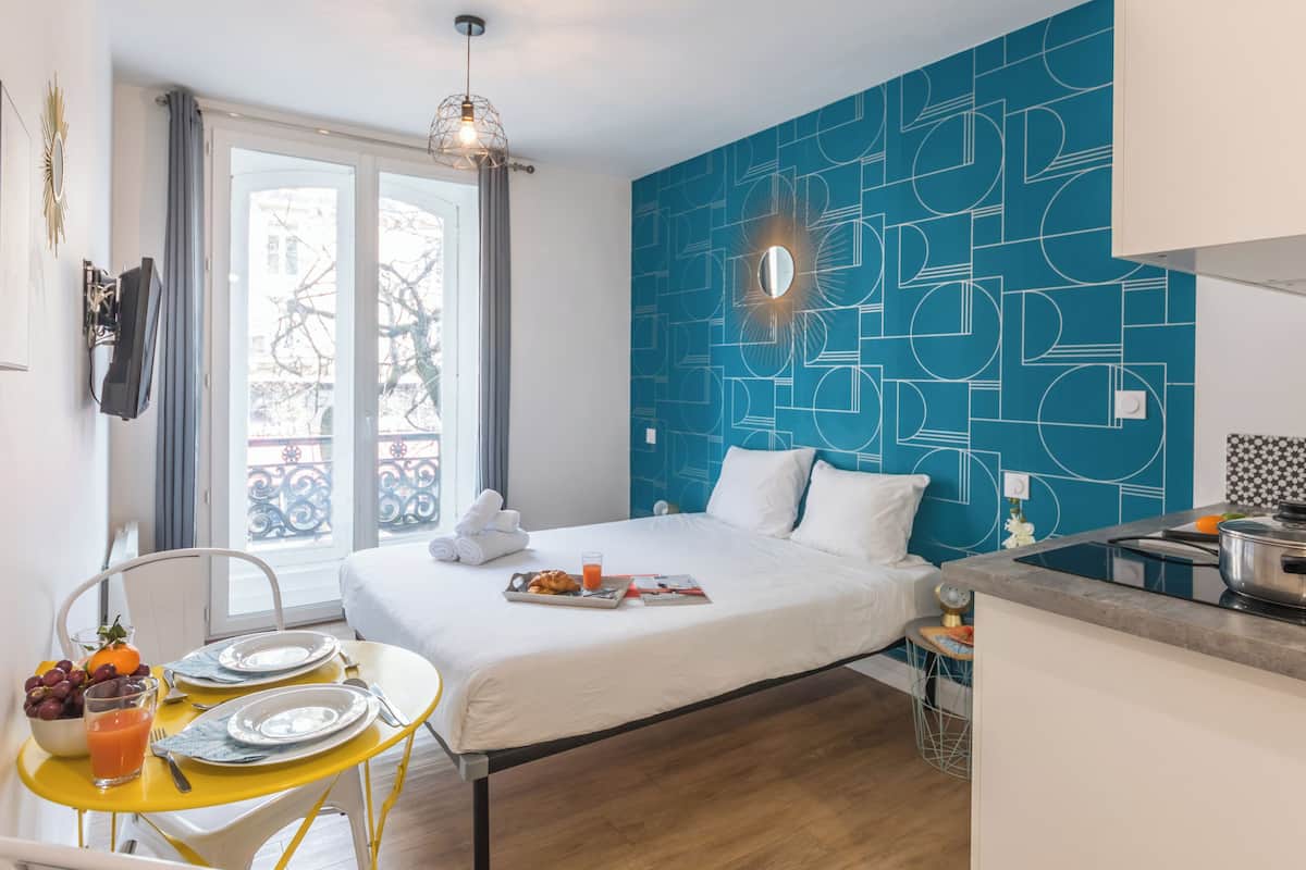 A hotel room with a bed, breakfast setup, and a kitchen area.
