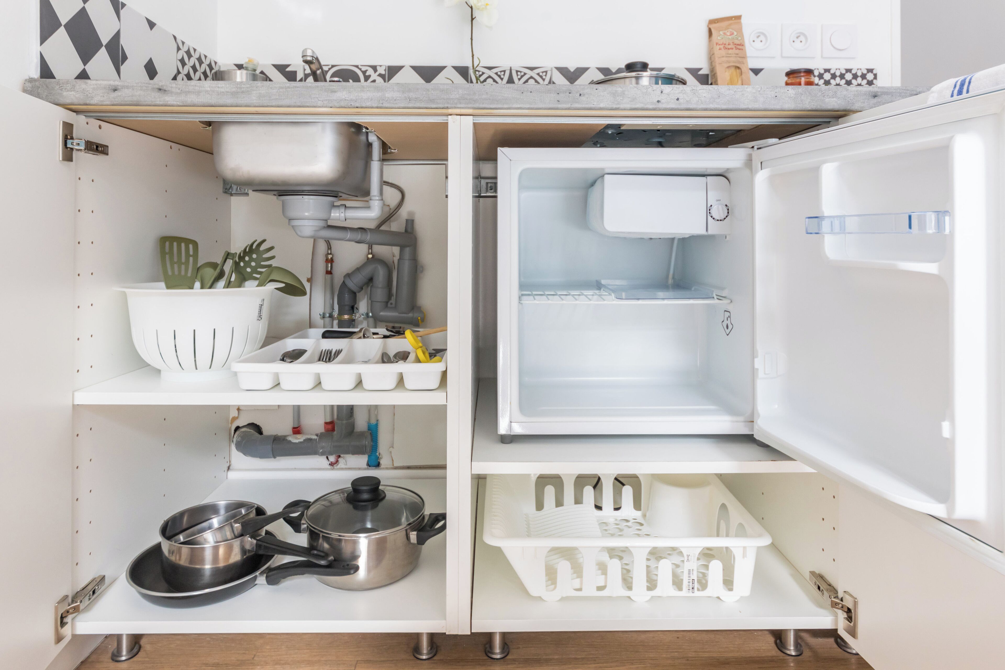 A kitchen with a built-in refrigerator, a sink, and various kitchen utensils and containers.