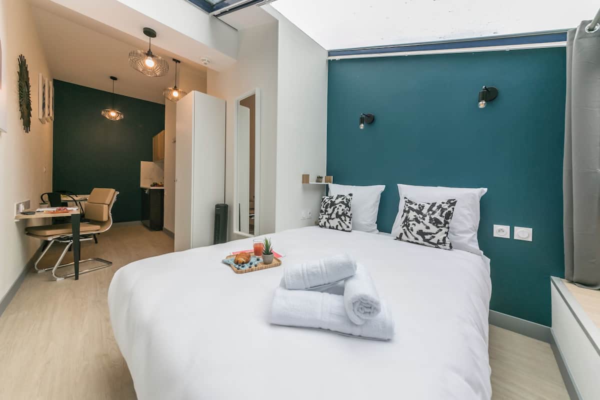 A modern hotel room with a large bed, a desk, and a chair.