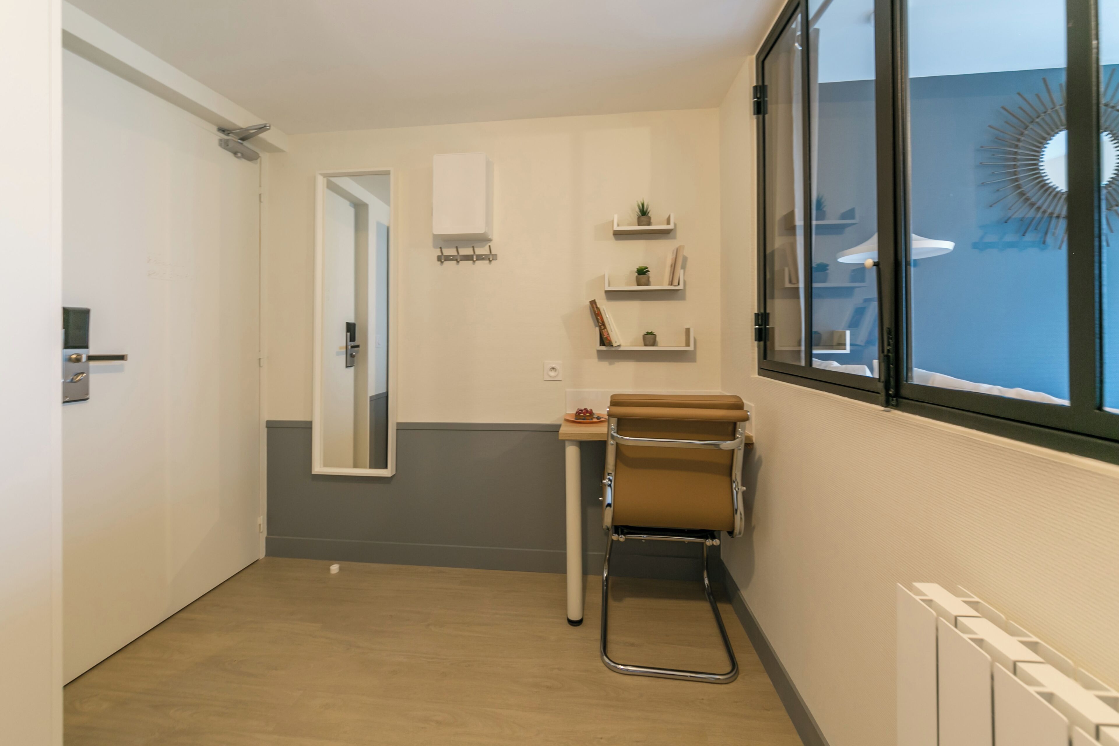 A small, modern bathroom with a mirror, a towel rack, and a radiator.