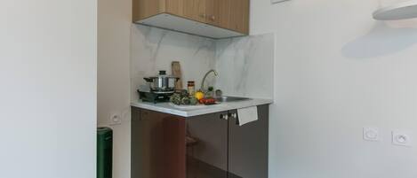 A compact kitchen with a built-in stove, a sink, and wooden cabinets.
