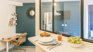 A modern kitchen with a breakfast setup including a plate, croissant, bowl of grapes, and a glass of orange juice. - WS Tour Eiffel - Nicolo (Paris)