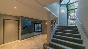 A modern interior with a staircase, a glass door, and a fire extinguisher. - WS Tour Eiffel - Nicolo (Paris)
