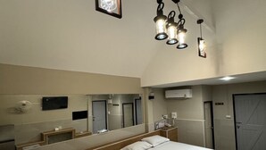 A hotel room with two beds, a large mirror, a TV, and a ceiling light fixture.