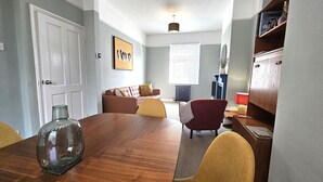 Un comedor con una mesa de madera, sillas, un florero y un sofá.