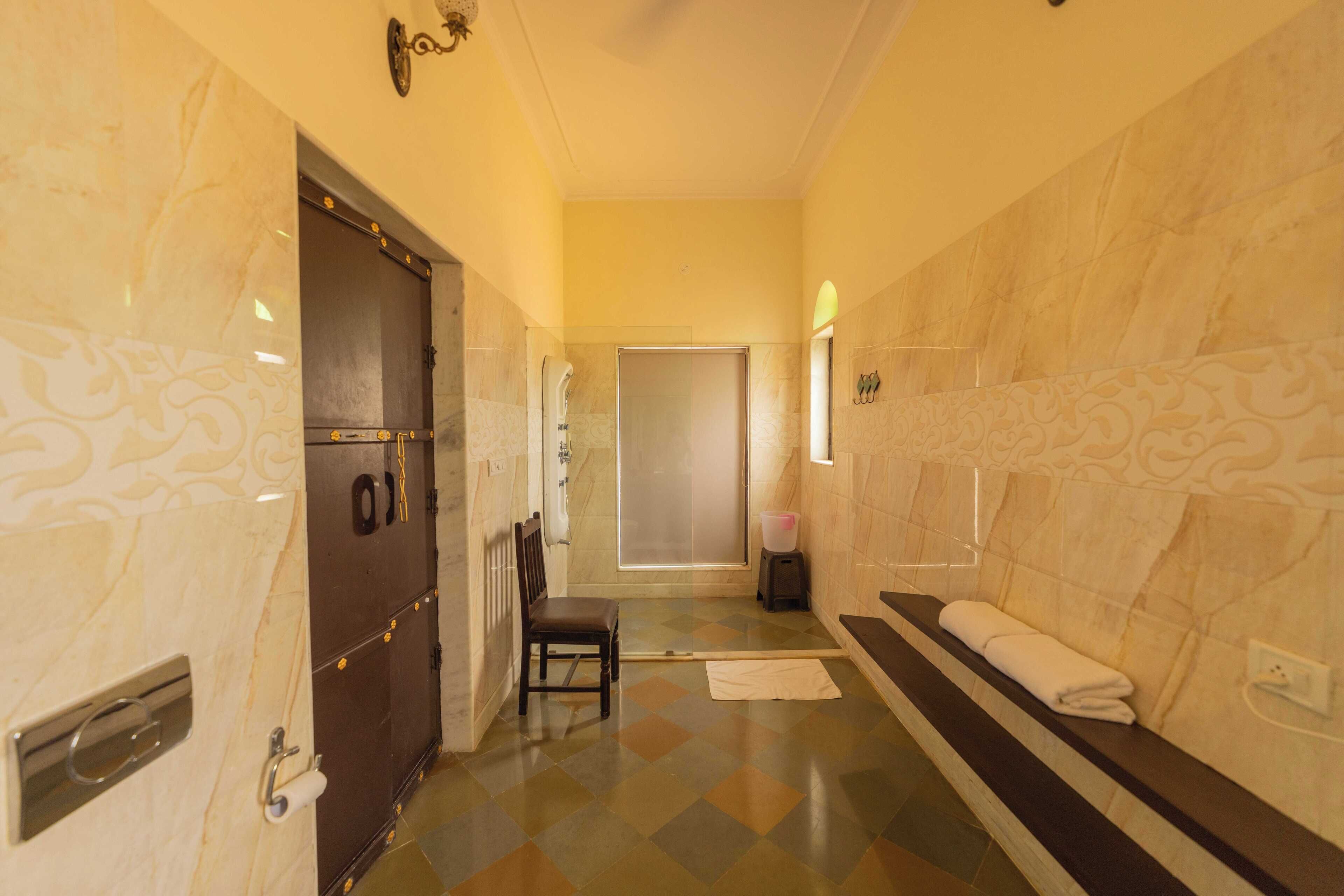 A hotel bathroom with a marble floor, a towel rack, and a shower area.