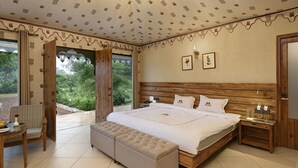 A bedroom with a large bed, wooden headboard, and a view of greenery outside.
