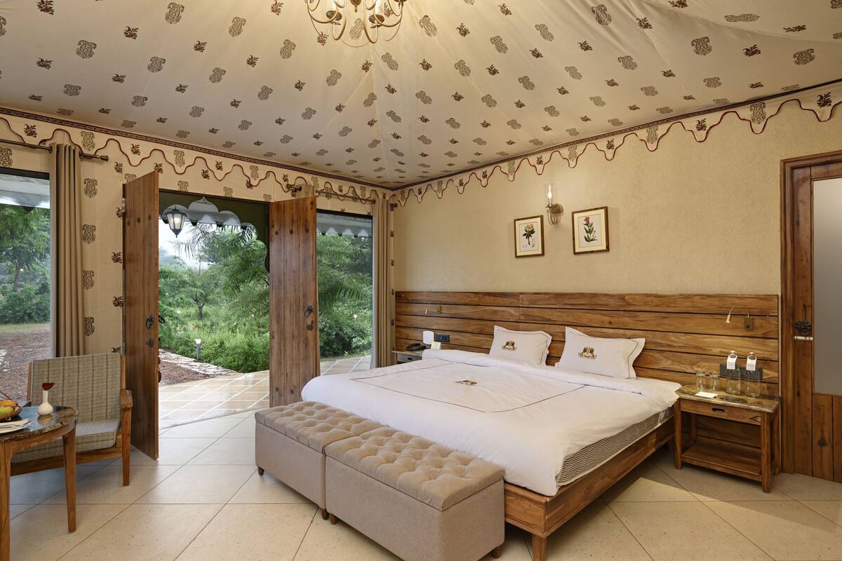 A bedroom with a large bed, wooden headboard, and a view of greenery outside.