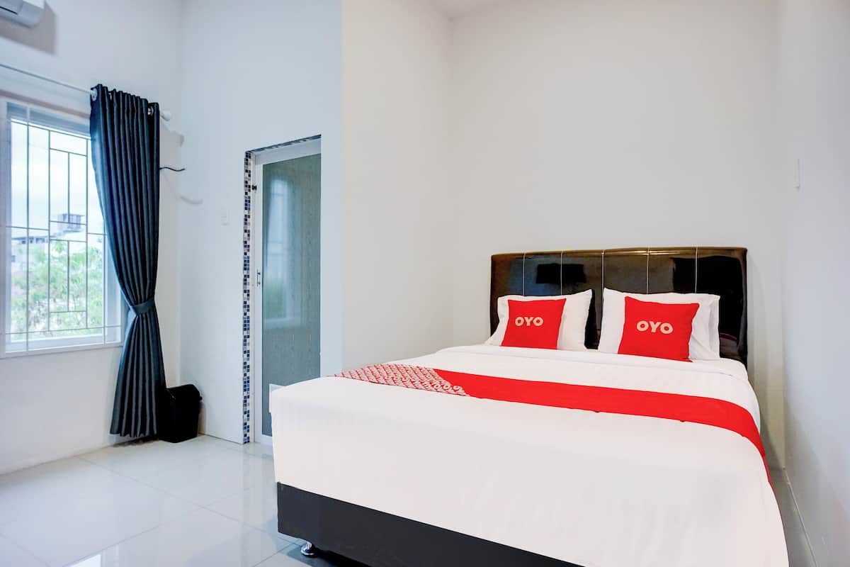 Hotellihuone, jossa on sänky, ikkuna verhoilla ja ovi.