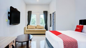 Une chambre d’hôtel avec un lit, un canapé, une télévision et une petite table.